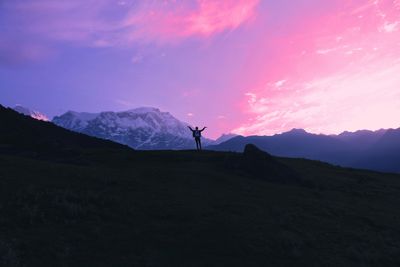 a silhouette of a person standing on hill